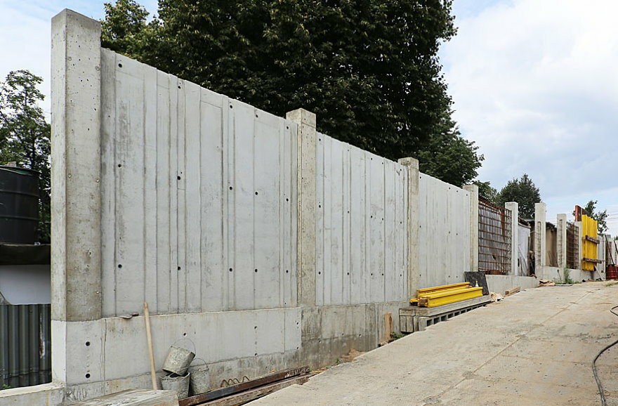 Monolitinė gelžbetoninė tvora priešais priemiesčio zoną