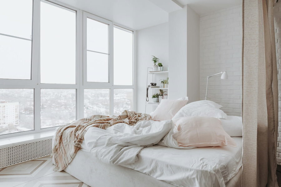 Französisches Fenster in einem weißen Schlafzimmer
