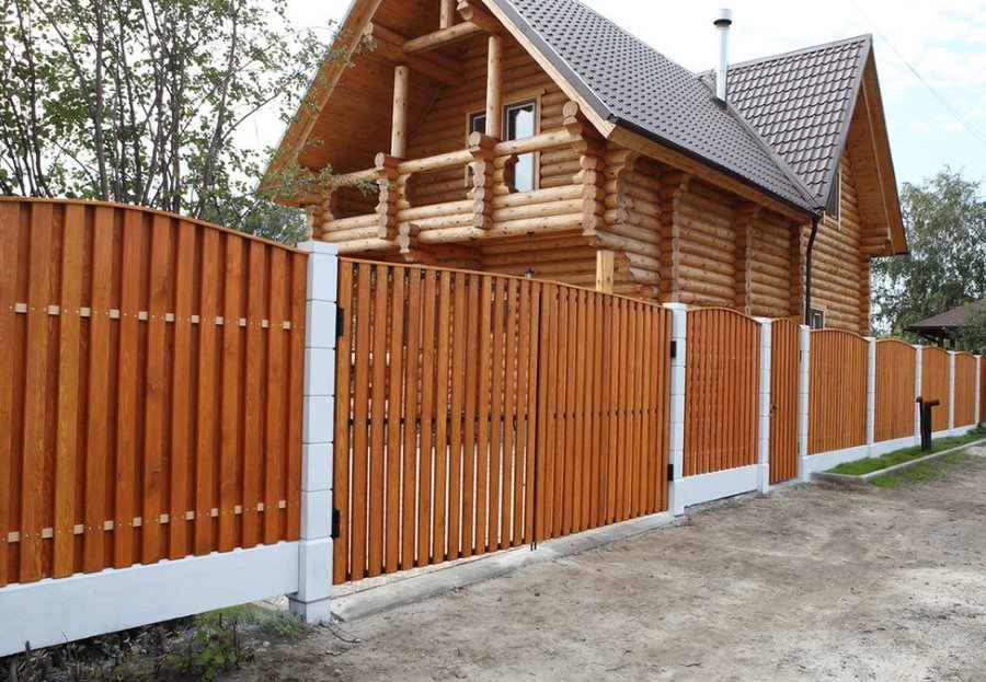 Wooden picket fence in the country with a log house