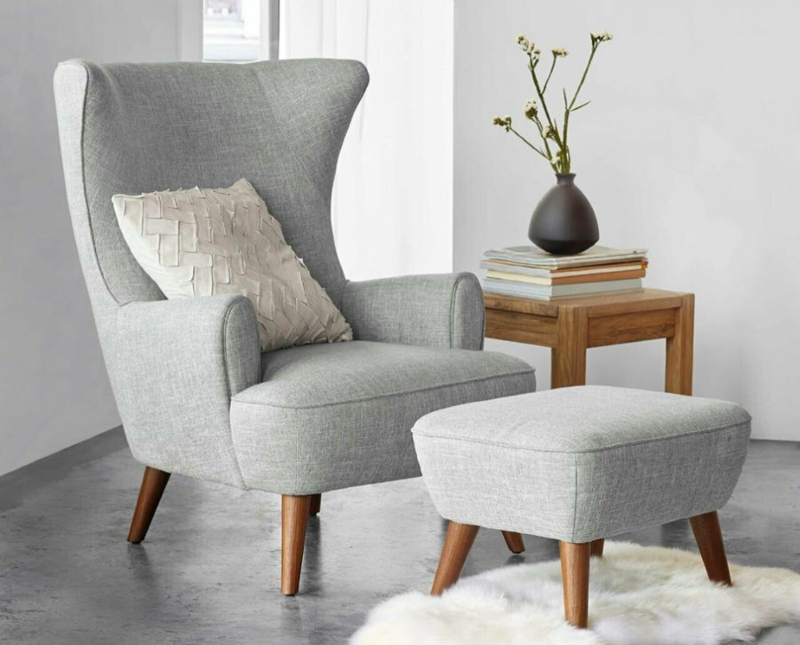 Upholstered armchair with small footrest
