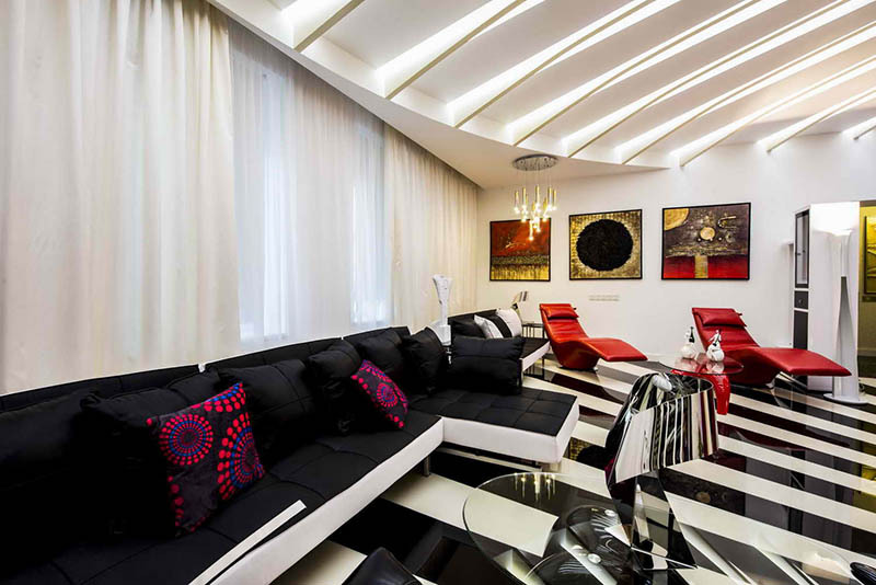 Oturma odasında, siyah beyaz dekorasyon, kırmızı ve altın aksanlarla zarif bir şekilde seyreltildi.