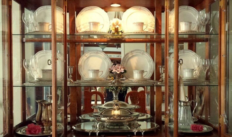Teeservice in den Regalen einer Glasvitrine im Flur