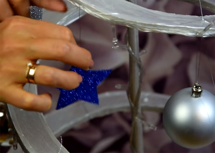 Joulukoristeet voidaan kiinnittää pahviin tavallisilla paperiliittimillä. Ripusta ilmapalloja ja muita koristeita spiraalin koko pituudelle. Voit käyttää myös kirkasta hopeaa