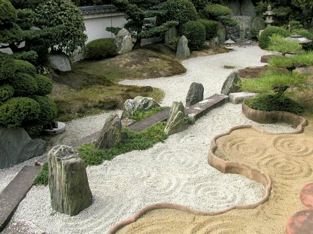 Fint spillror mellan stora stenar i en japansk trädgård