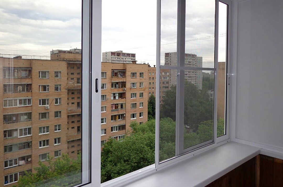 Çok katlı bir binanın dairesinde cam balkonun açık kanadı