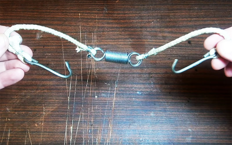 Binden Sie zwei Seilstücke an die Ringe und Haken - und schon ist der Klemmmechanismus für den Räucherdeckel fertig.