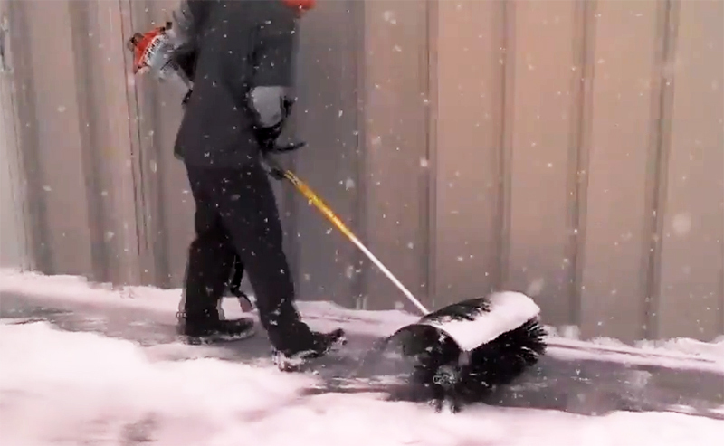 De gemotoriseerde borstel helpt bij het schoonmaken van het gebied na sneeuwval