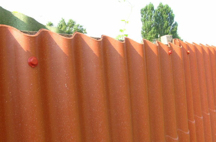 Bordas chanfradas de ardósia ondulada em uma cerca de um chalé de verão