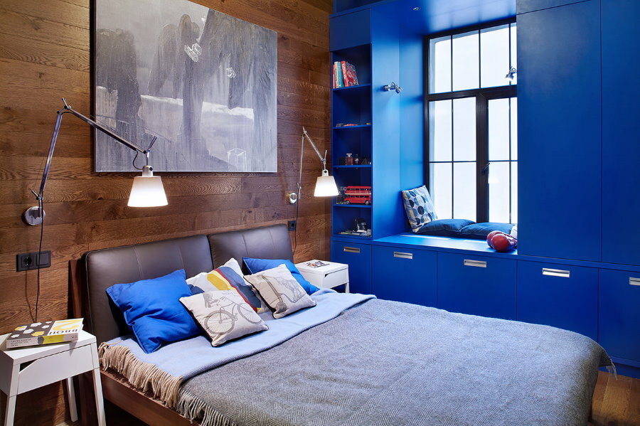 Niebieskie szafki wokół okna w pokoju dziecięcym