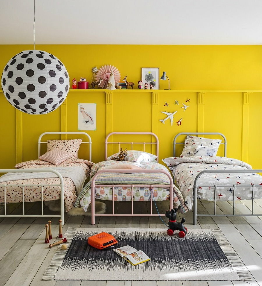 Lasten sängyt lähellä keltaista seinää