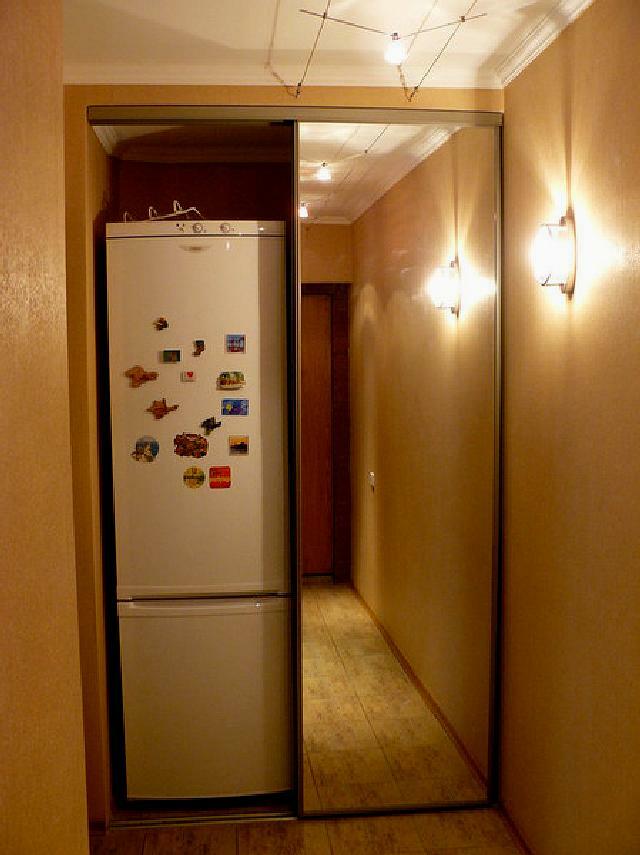 Spegelskåp nära ett smalt kylskåp