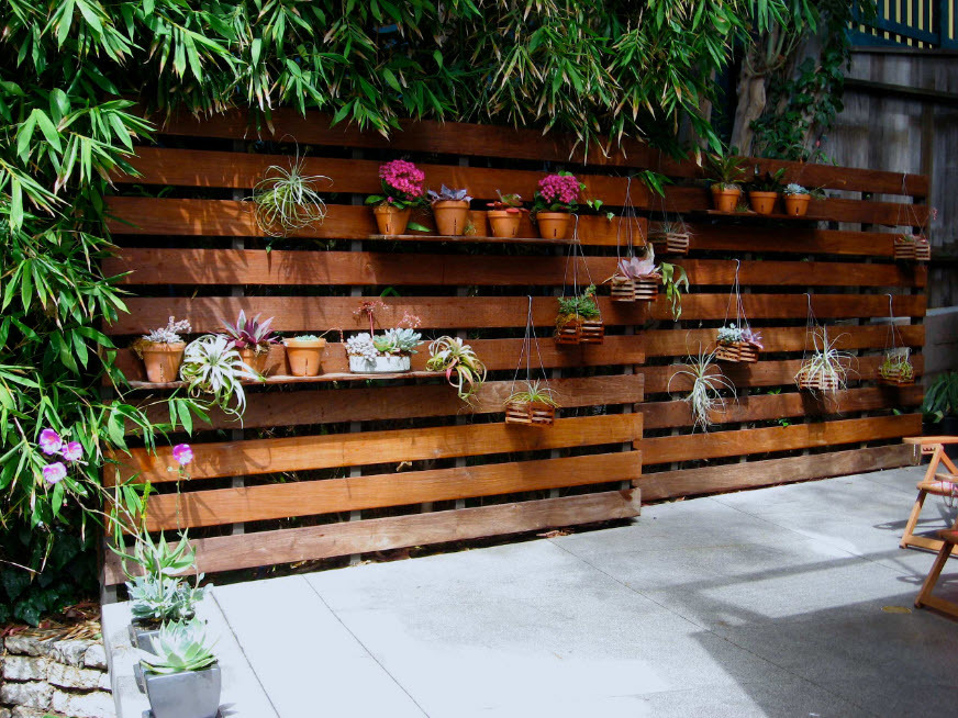 Fából készült kerítés dekorációja beltéri virágokkal