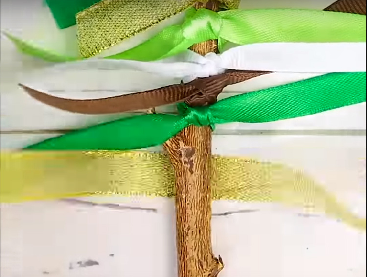 Nouez des rubans de couleurs différentes en deux nœuds sur la branche afin que les extrémités dépassent sur les côtés