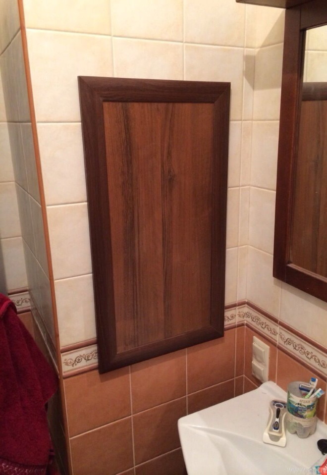 En dörr på ett toalettskåp med rör och diskar