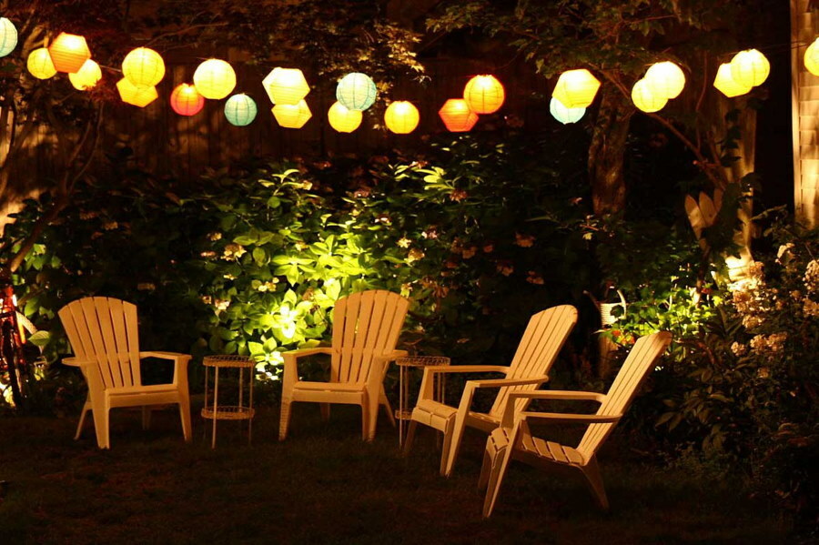 Sedie da giardino sotto una ghirlanda di piccole lanterne