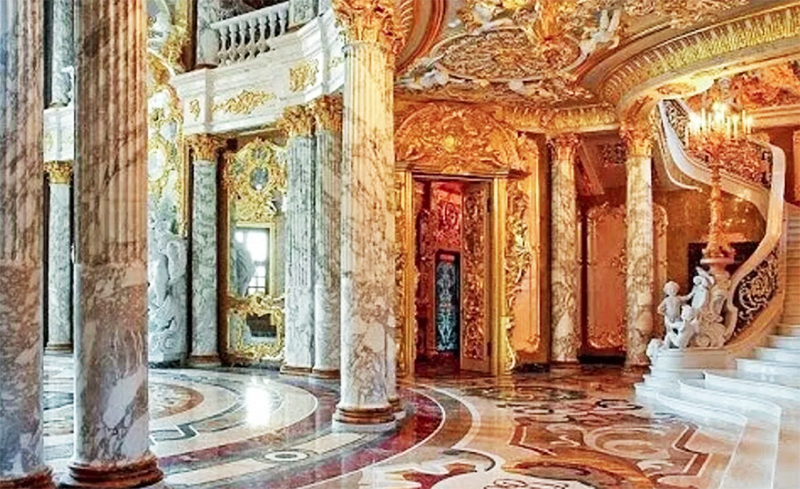 En lyxig böjd trappa av naturlig marmor, dekorerad med ängelfigurer, leder till andra våningen.