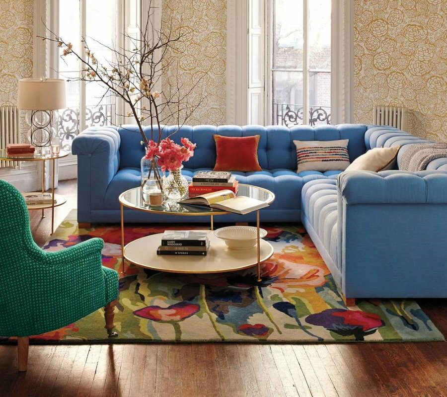 Krāsains paklājs stūra dīvāna priekšā