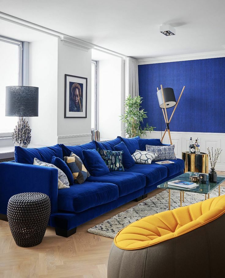 Dzeltens atzveltnes krēsls viesistabā ar zilu dīvānu