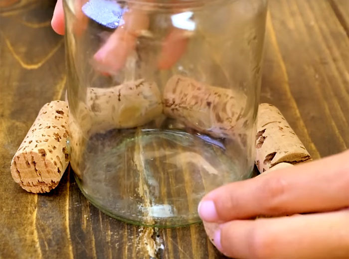 Using hot glue, fix the corks, starting from the bottom, in a circle on the surface of the can