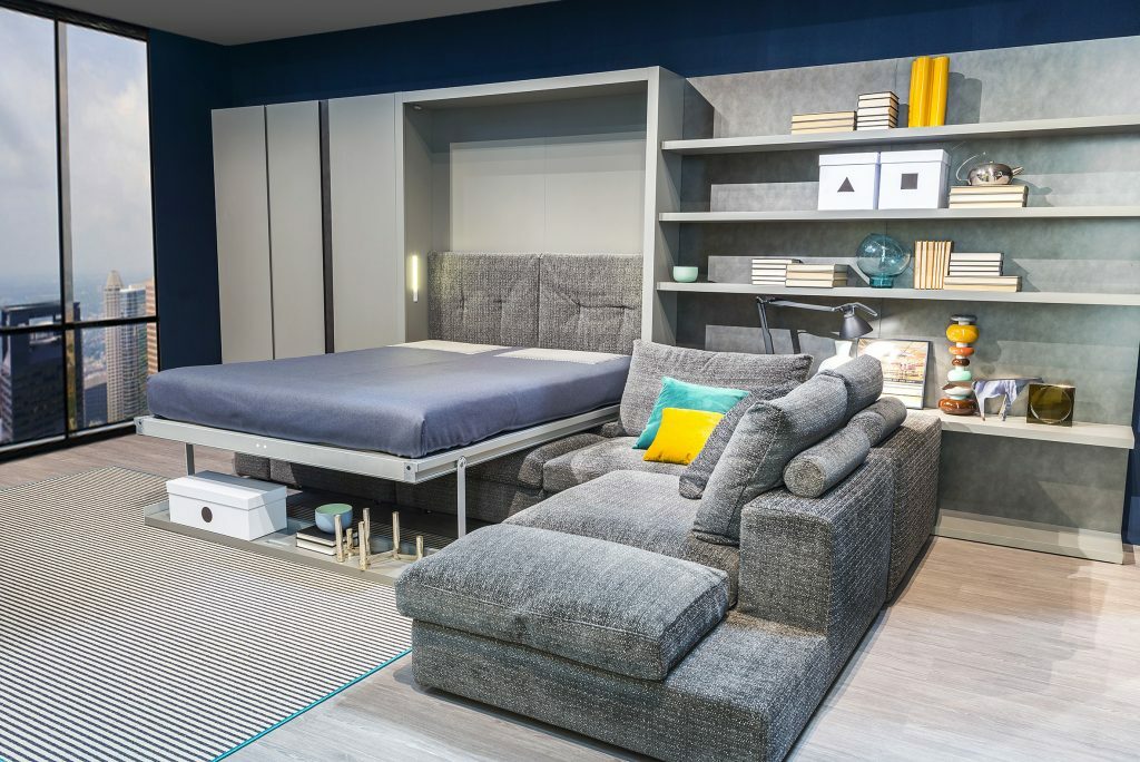 Sammenleggbar seng i stuen i en leilighet med et stort vindu