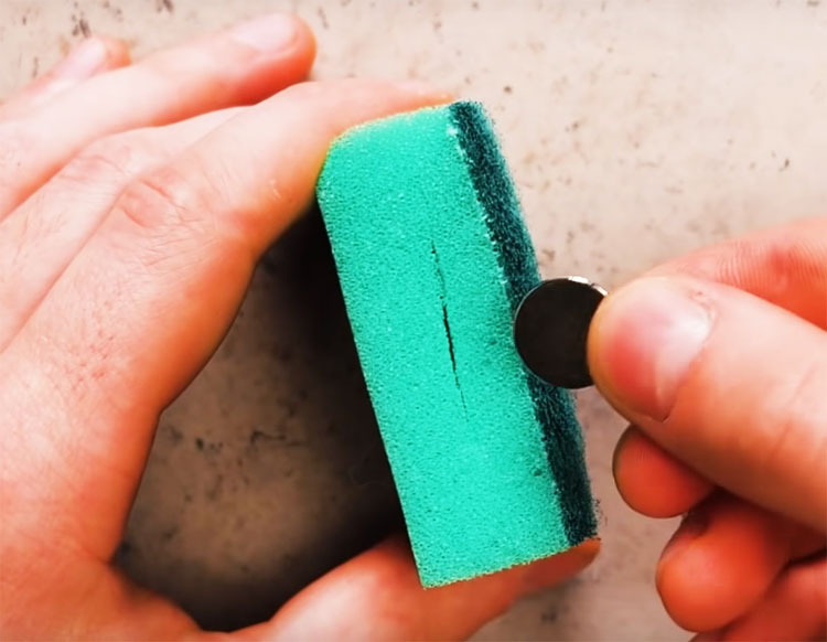 Machen Sie Schlitze in beiden Seiten des Schwamms und stecken Sie einen kleinen Magneten in eine und eine normale Münze in die andere.