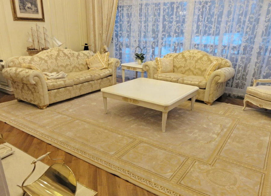 Gaismas zīda paklājs zālē dīvāna priekšā