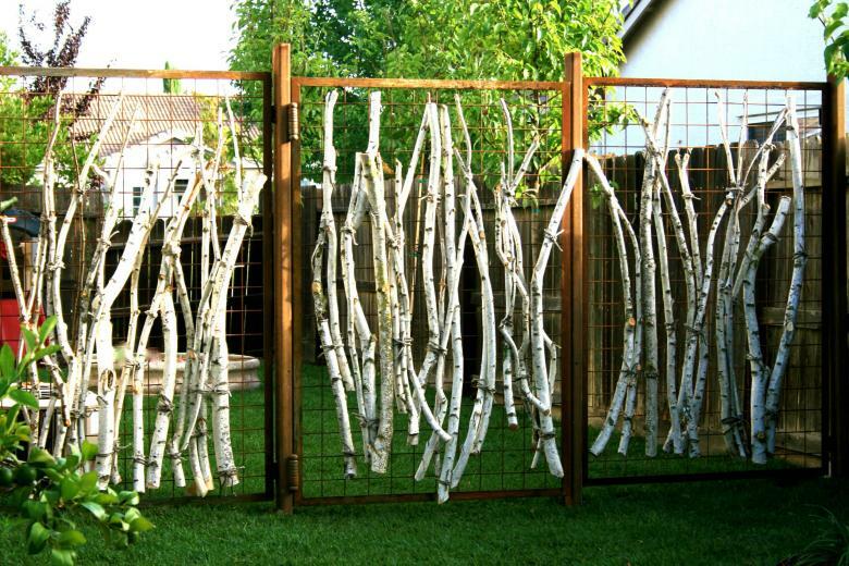 Galhos de bétula em uma cerca de jardim feita de uma rede de arame