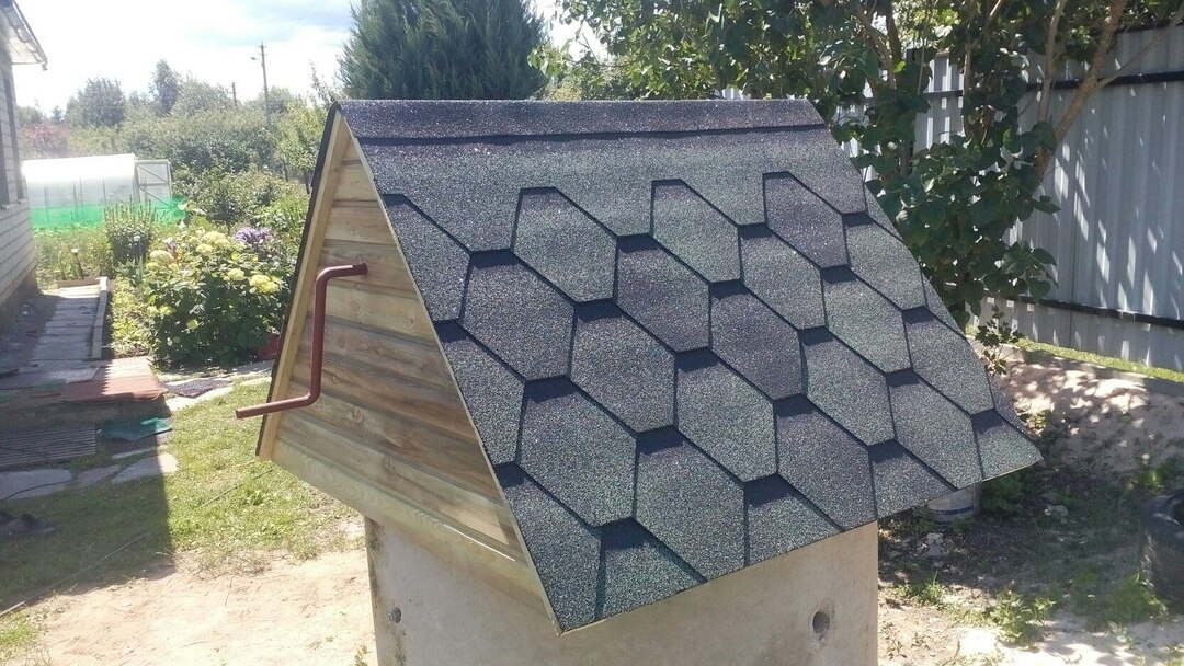 Lite hus med tak laget av myke fliser på en brønn