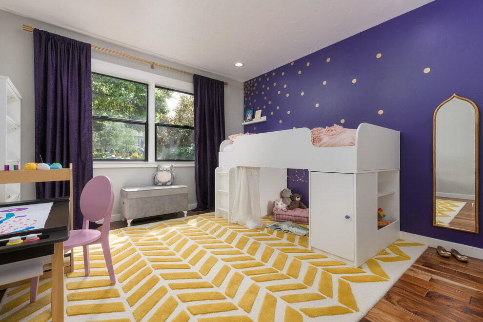 Vysoká dětská postel na pozadí fialové zdi