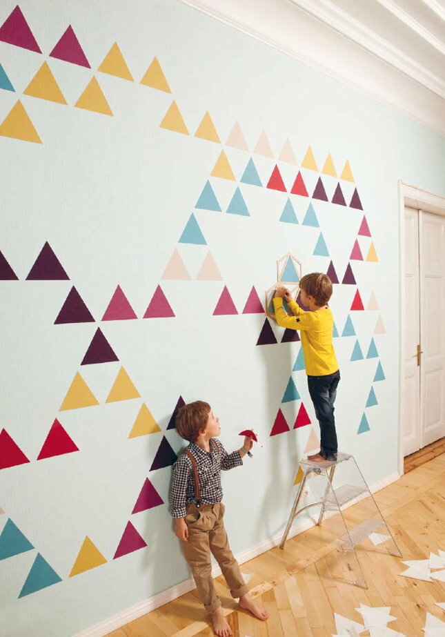 Bērnudārza baltās sienas dekorēšana ar daudzkrāsainiem trīsstūriem