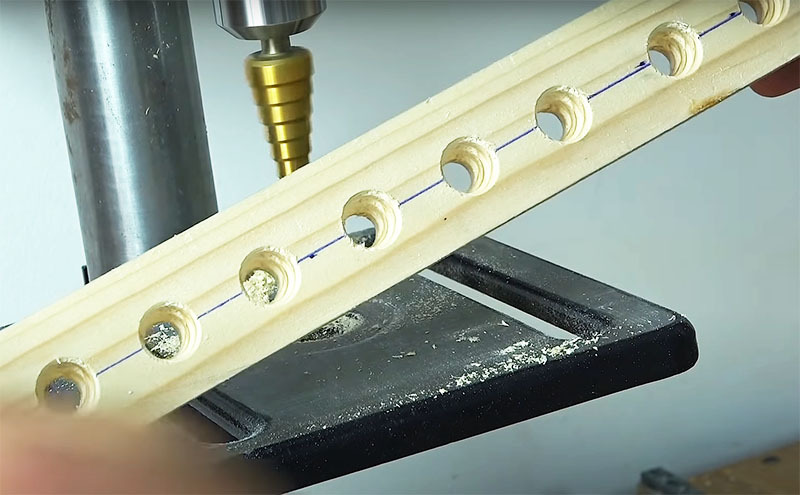 A base da ferramenta é o mesmo trilho de madeira com orifícios para baterias