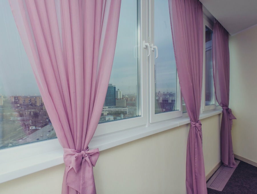 Lyserøde gardiner på vinduerne på den isolerede altan