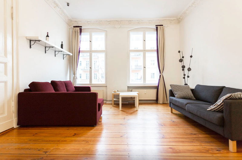 Světlé povrchy, velká okna, vysoké stropy a minimum nábytku vizuálně činí obývací pokoj trochu prostornějším