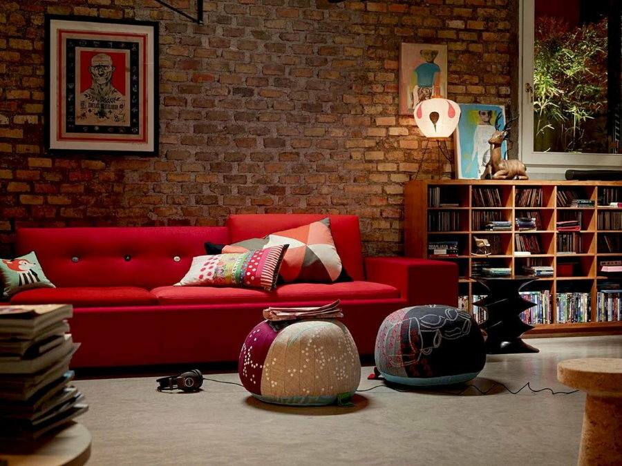 Piros kanapé egy szobában, téglafal utánzásával