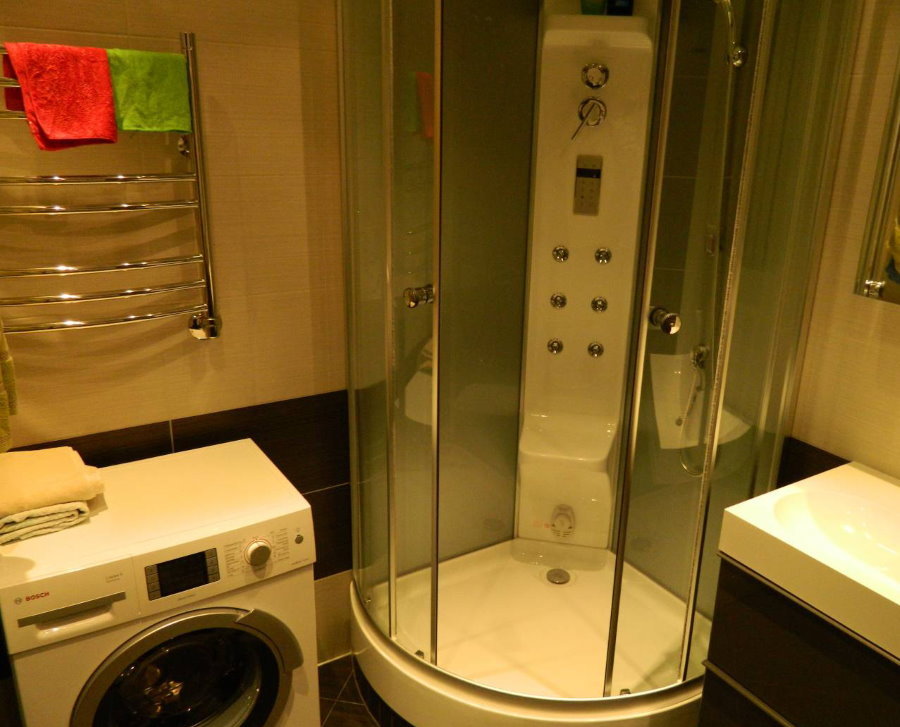 תא מקלחת קומפקטי בחדר הרחצה עם מכונת כביסה