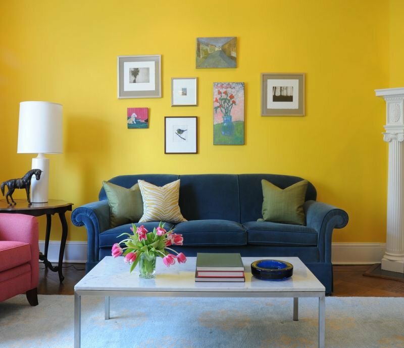 Zils dīvāns uz dzeltena sienas fona