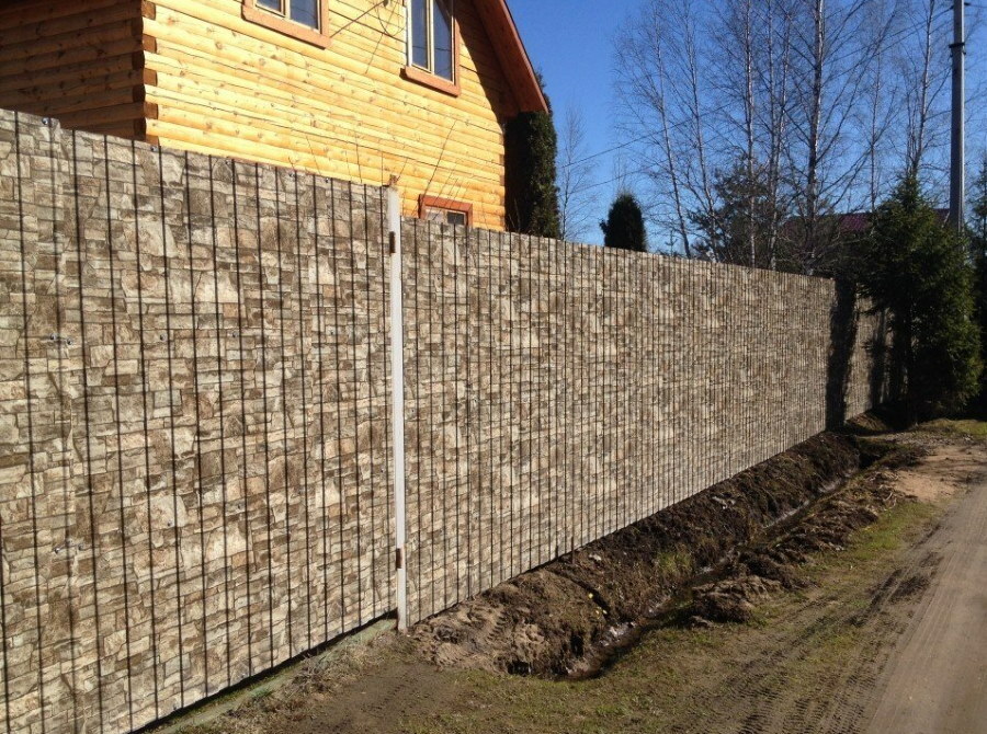 Zaun aus Lattenzaun mit Naturstein beschichtet