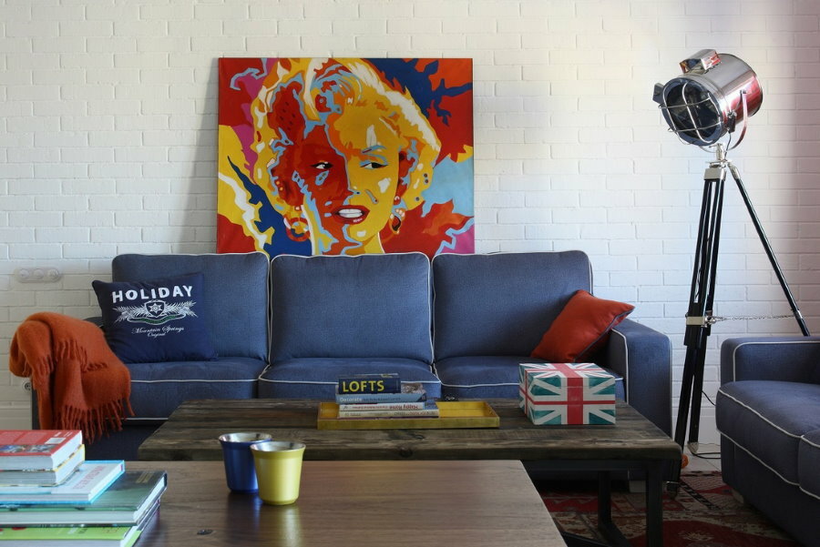 Zils dīvāns popmākslas stila dzīvojamās istabas interjerā