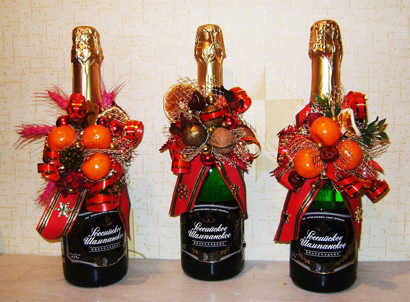 Pour décorer des bouteilles comme celui-ci, vous aurez besoin des noix, des cônes, des bonbons, des mandarines et des rubans décoratifs.