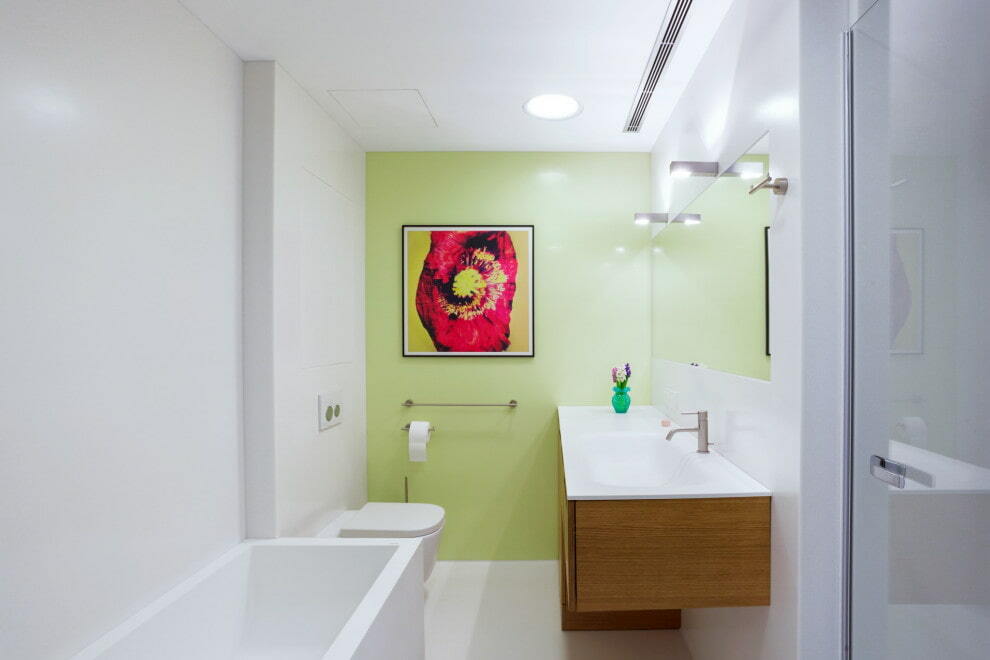 Bright painting on a light green wall in the bathroom