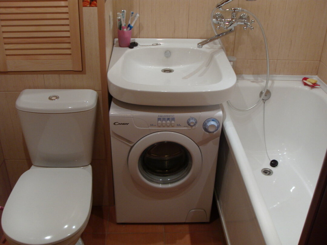 Tvättmaskin under porslinets handfat i badrummet