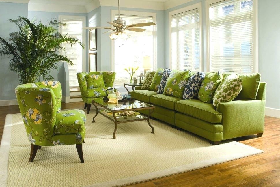 Dekoratīvie spilveni uz zaļa dīvāna zālē