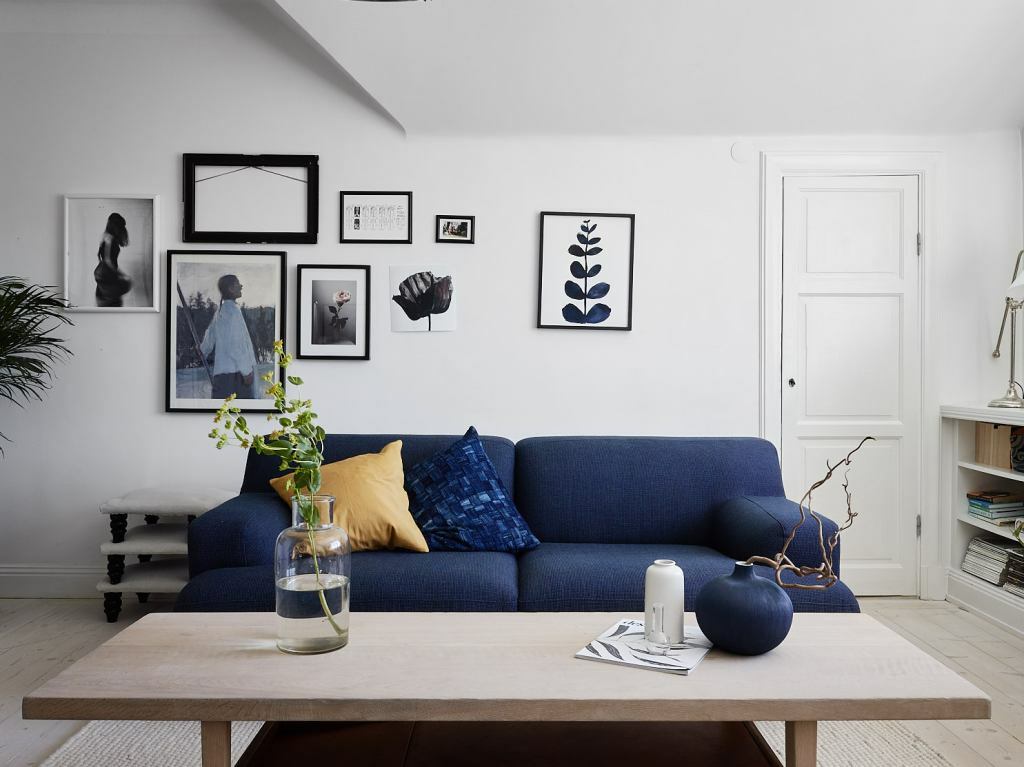 Oturma odasının beyaz duvarlarının arka planında mavi kanepe