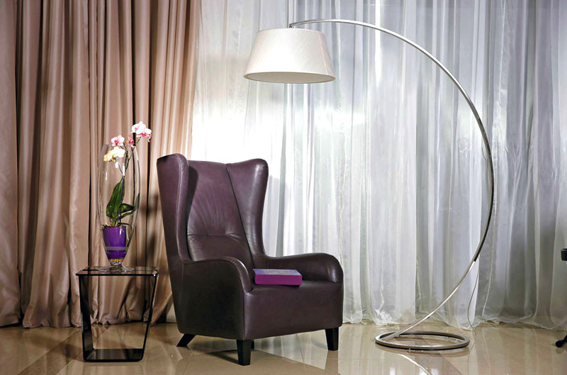 Anastasia's favorite place is a luxurious armchair with ears in the English style, next to which they put a floor lamp on a curved chrome leg
