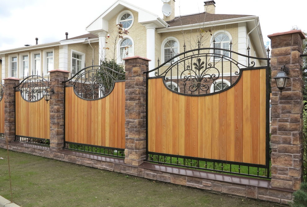 Wooden fence with wrought elements on stone pillars