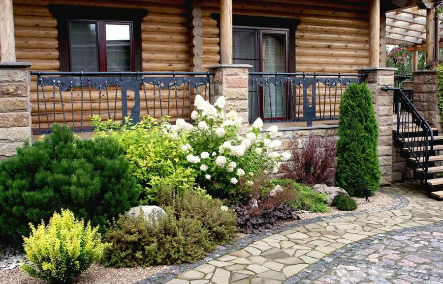 Narrow mixborder in front of the porch with forged railings