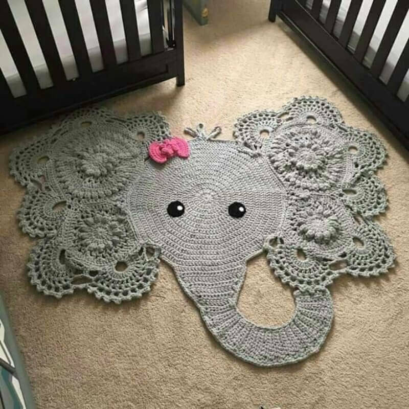 Knitted rug in the form of an elephant in front of baby cots
