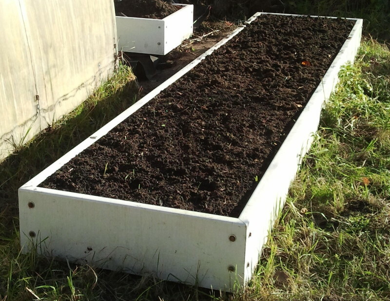 PVC dārza gulta ar melnu augsni viņu vasarnīcā