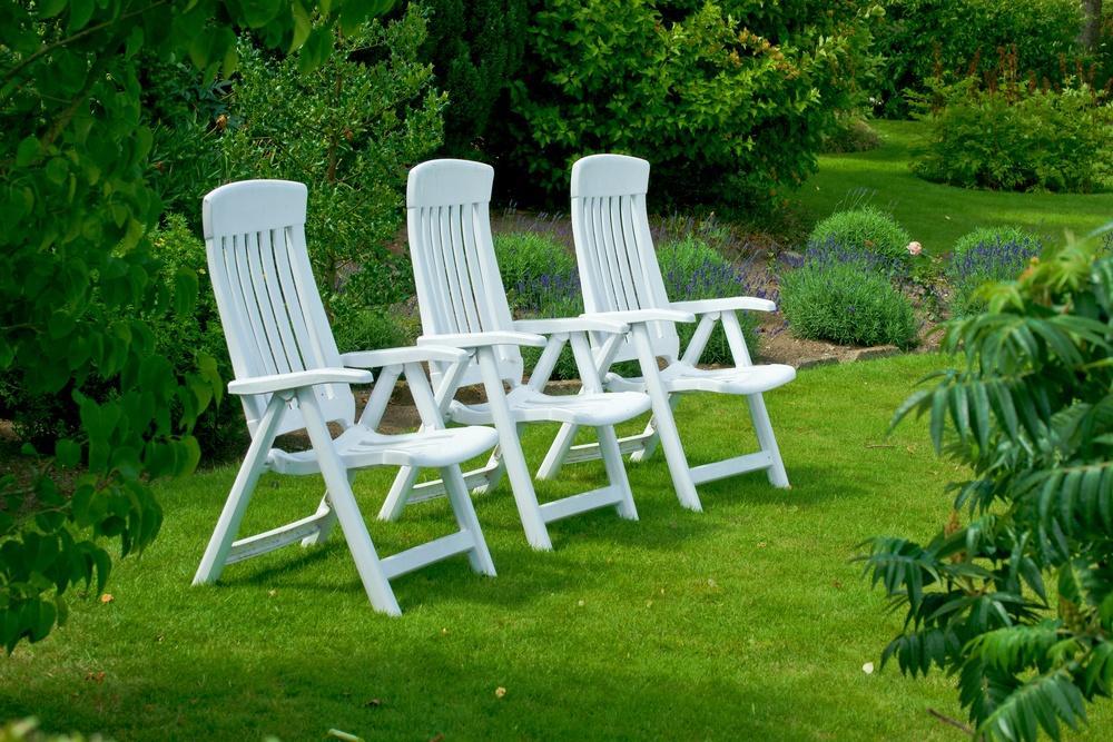 Białe krzesła ogrodowe na trawniku w parku