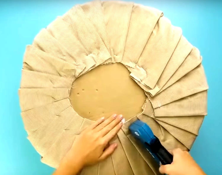 Secure the drapery on the underside of the pouf with a furniture stapler